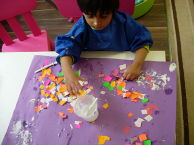 Making a colourful collage with glue at paper Early Learners' Nursery School, Leicester